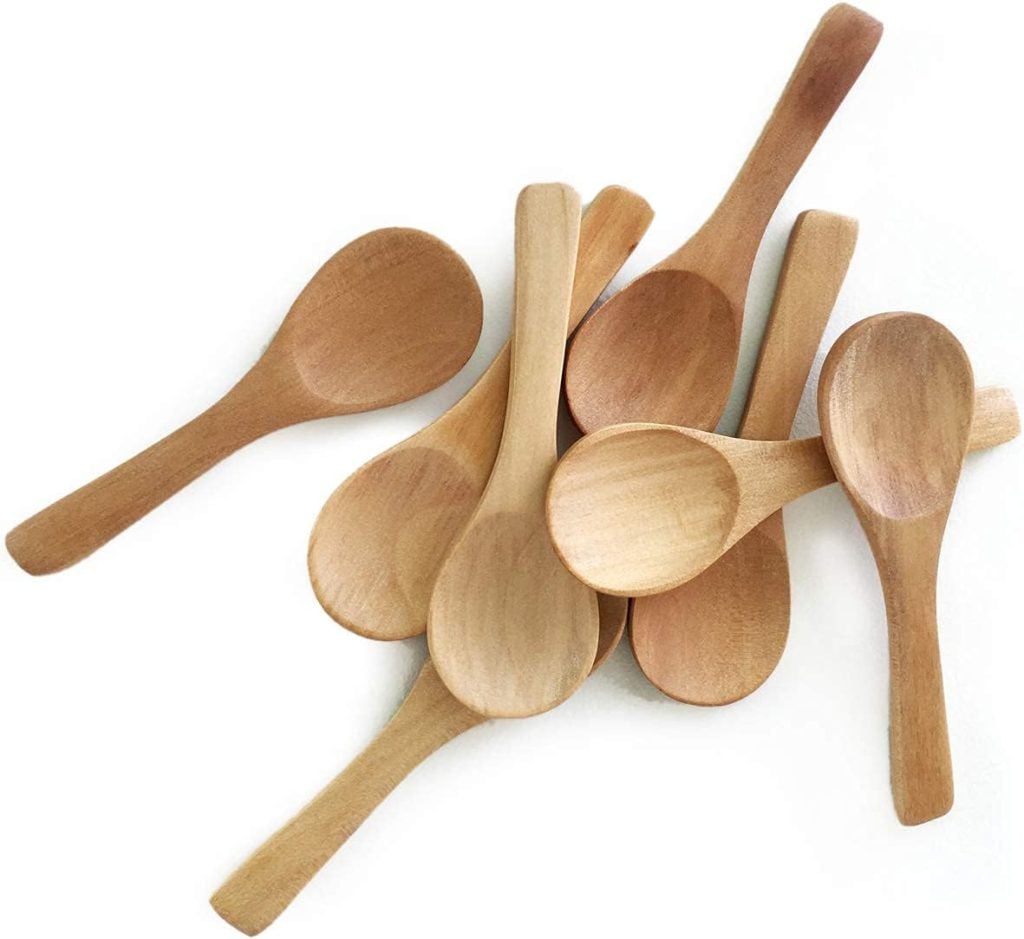 A group of small, unfinished wooden spoons scattered on a white surface.