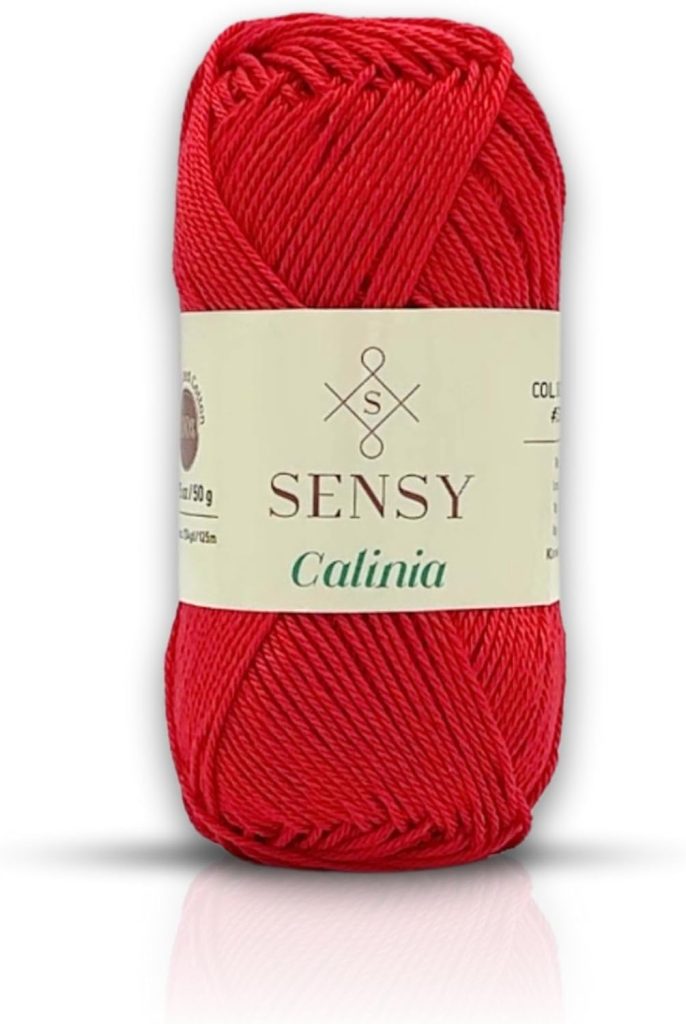 A skein of red Sensy Catlinia yarn with a cream label wrapped around it, displaying the brand name and product details.