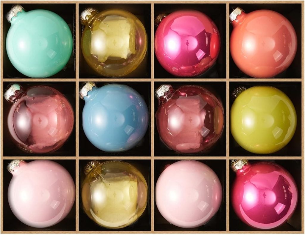 A grid of twelve Christmas ornaments in various pastel and bright colors, each placed in its own compartment.