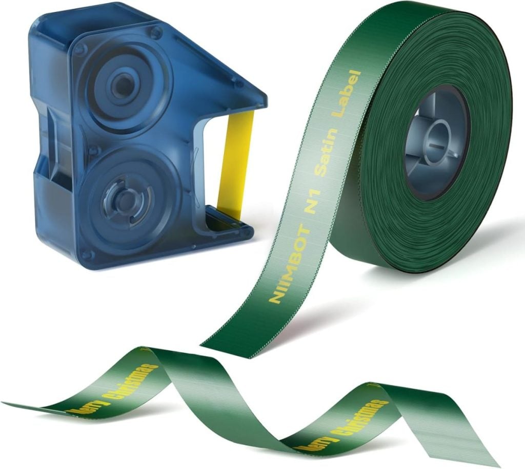 A blue label tape dispenser and a green roll of label tape marked “NIMBOT N1 Satin Label” with yellow text are shown against a white background.