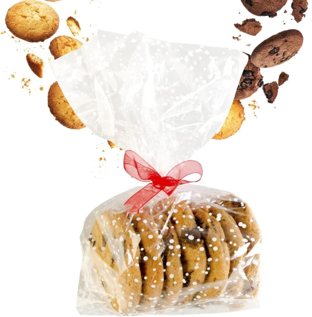 A clear plastic bag tied with a red ribbon contains cookies, with additional cookies and crumbs scattered in the background.