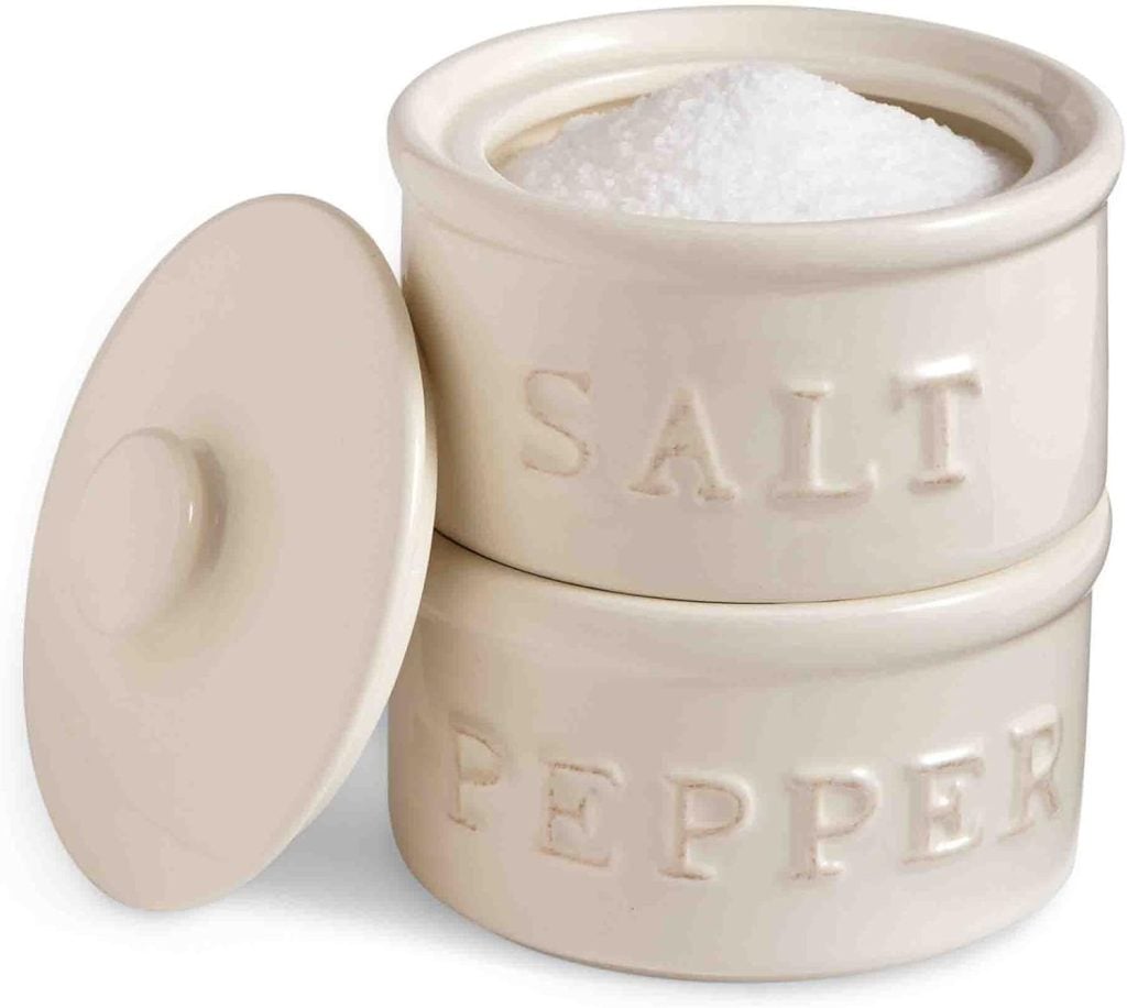 Two stacked ceramic containers labeled "Salt" and "Pepper," with the top open and filled with salt; the lid is set aside&mdash;perfect for styling food blog posts.