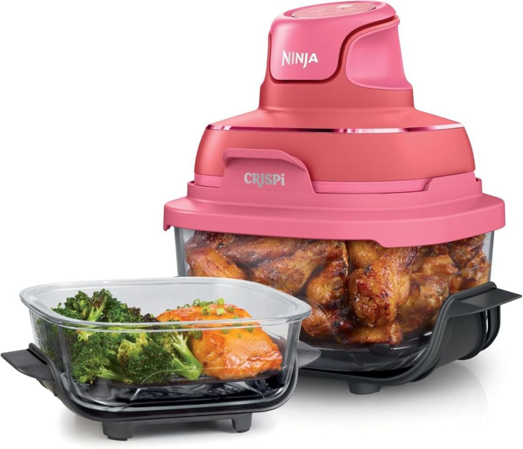 A pink Ninja CRISPI air fryer filled with cooked chicken sits next to a glass container holding broccoli and a cooked orange dish—perfect as a thoughtful hostess gift for any food lover.