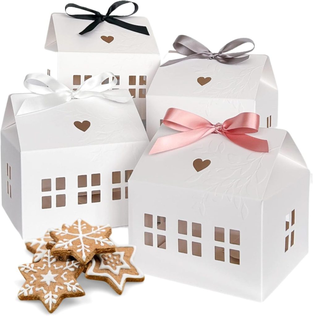 Four white house-shaped gift boxes with heart cutouts and different colored ribbons, placed beside decorated star-shaped cookies.