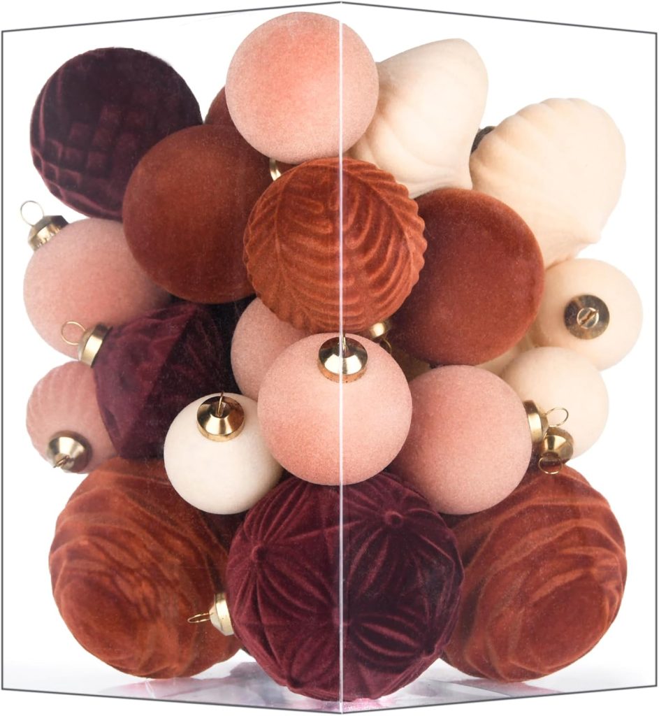 A cluster of velvet and matte Christmas ornaments in shades of red, pink, cream, and burgundy, displayed against a white background.