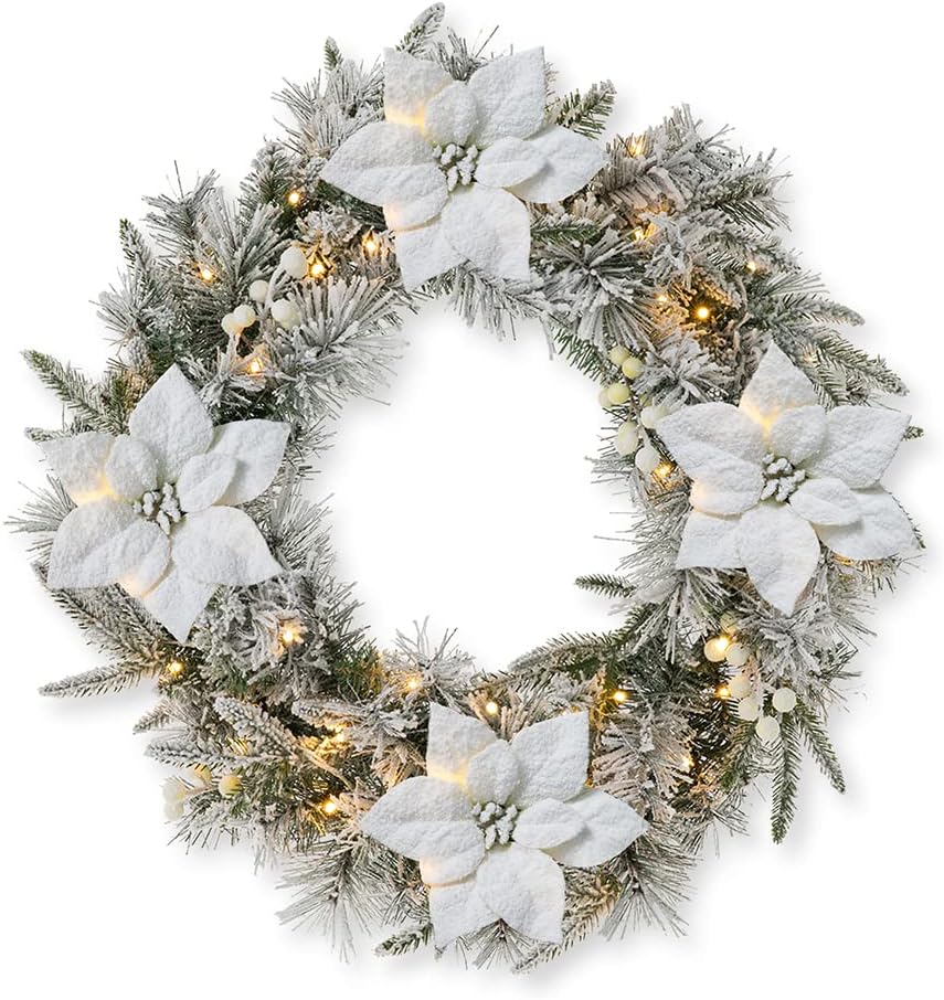 A frosted holiday wreath decorated with white poinsettias, artificial pine branches, white berries, and warm white string lights creates stunning window art for a festive touch.