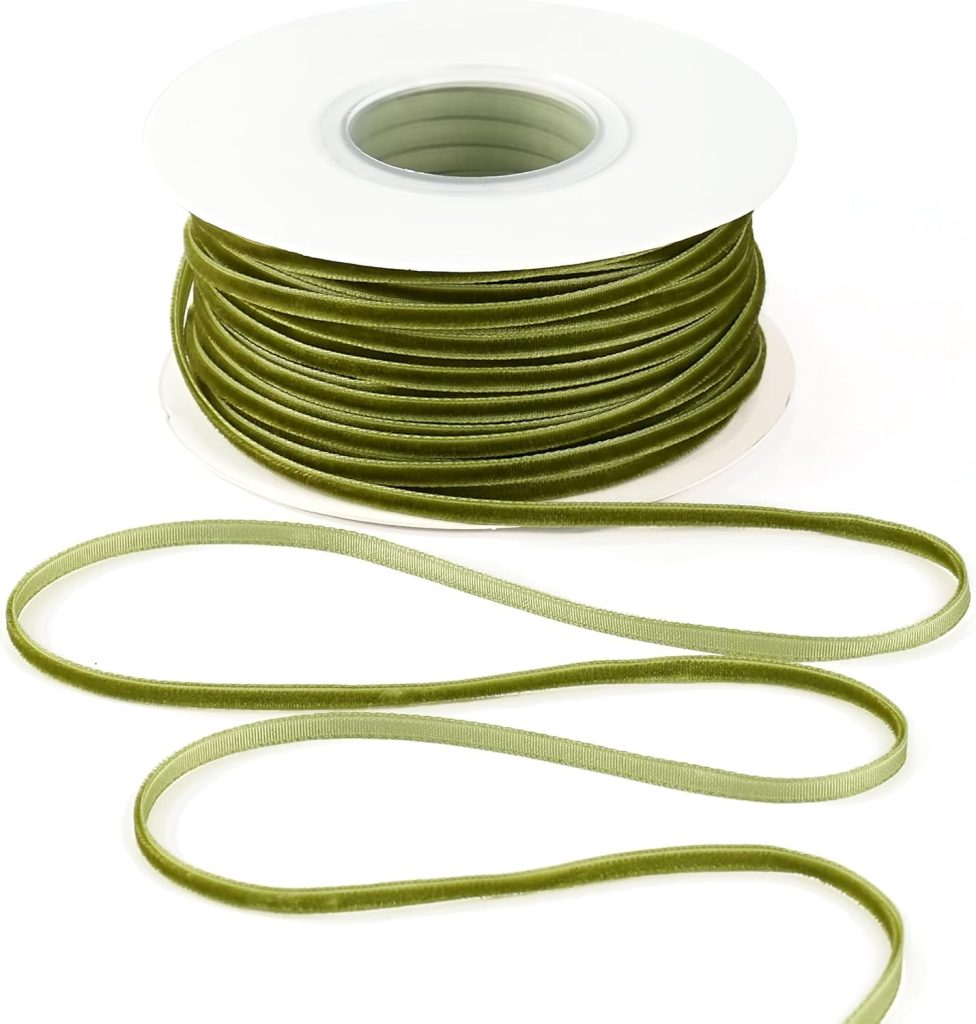 A spool of olive green velvet ribbon with a length of ribbon unspooled and arranged in front.