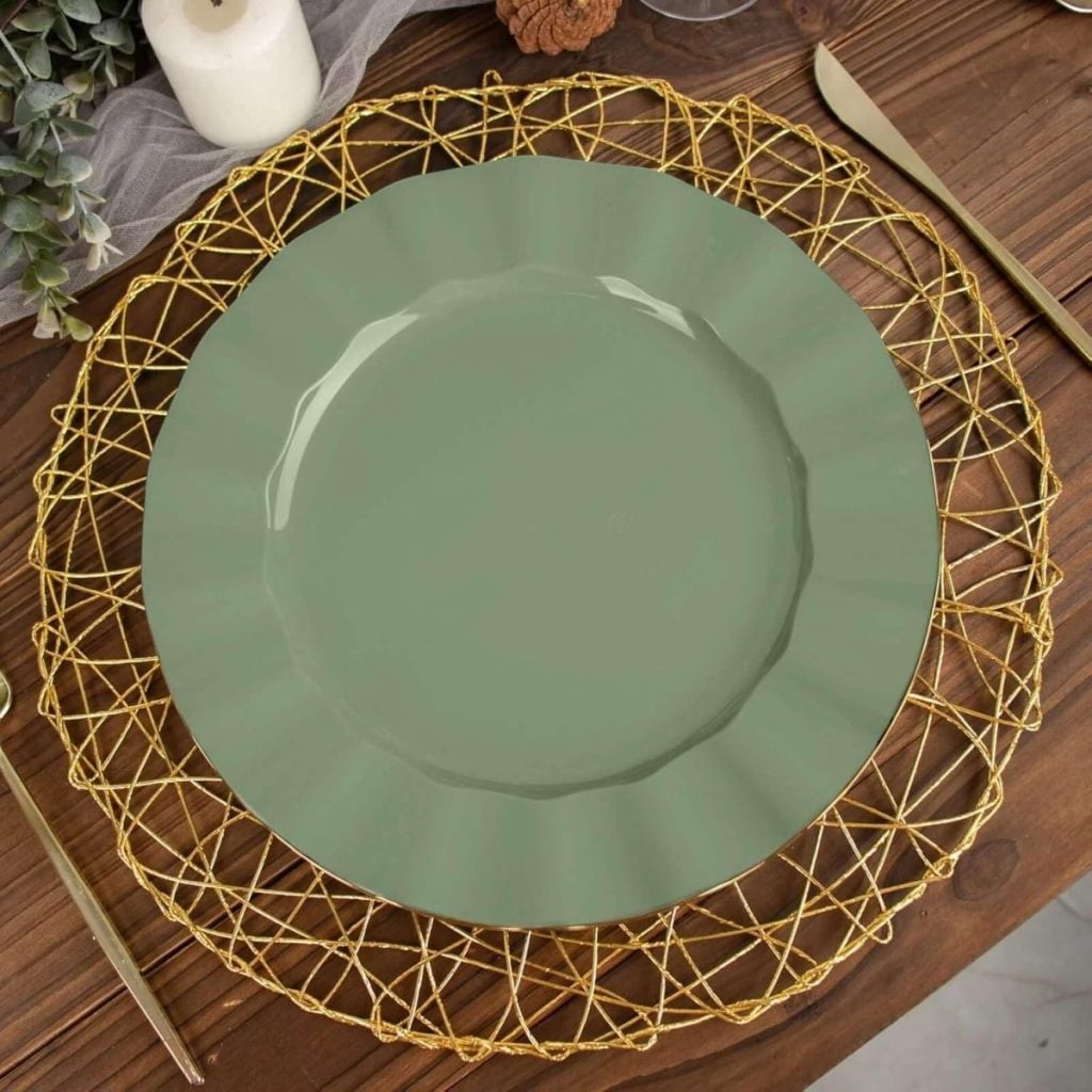 A green plate sits on a decorative gold woven placemat, with a gold knife and fork on either side, on a wooden table.