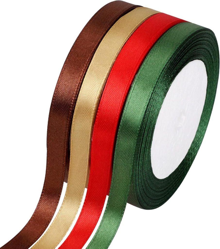 Four rolls of satin ribbon in brown, gold, red, and green colors are stacked side by side, partially unspooled.
