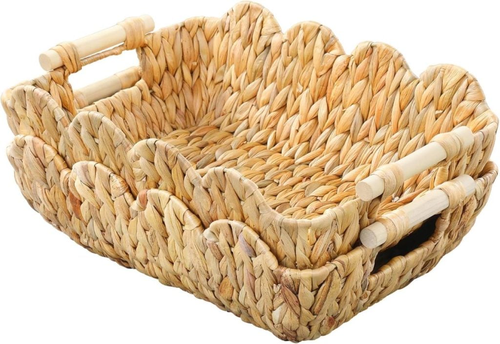Two woven wicker baskets with handles are nested together, featuring a scalloped edge and natural fibers.