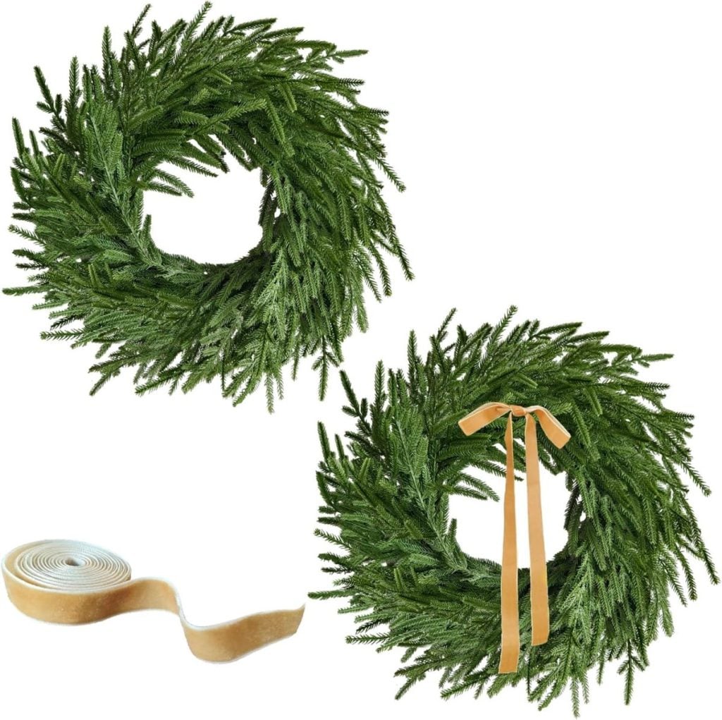 Two artificial green wreaths are displayed as charming window art, one adorned with tan ribbon and one plain. A roll of tan ribbon sits beside them on a white background.