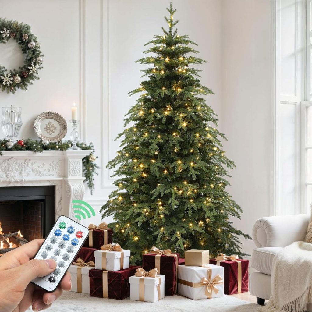 A hand holds a remote control in front of a decorated Christmas tree with lights, surrounded by wrapped gifts in a living room with a fireplace and wreath.