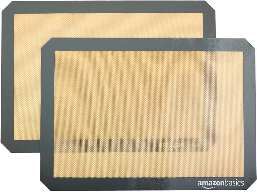 Two rectangular silicone baking mats with black borders, branded "AmazonBasics," are stacked slightly offset against a white background.