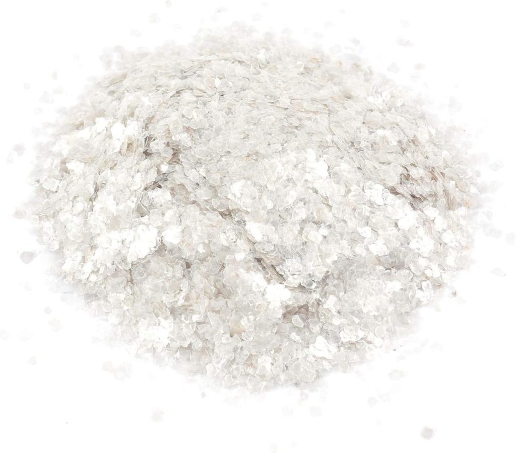 A pile of translucent, flaky, white mineral pieces scattered on a white surface—perfect as a unique hostess gift for those who appreciate natural beauty.