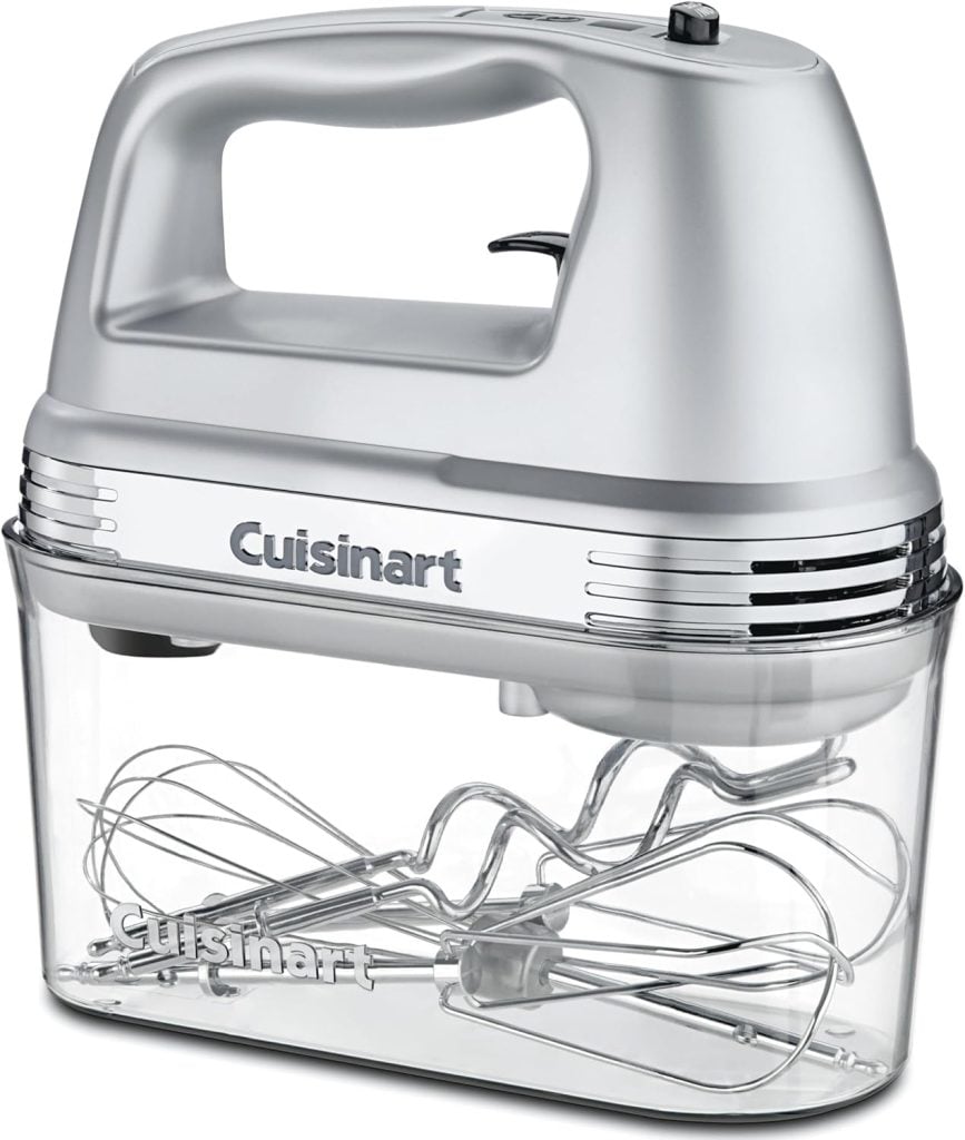 A silver Cuisinart electric hand mixer is shown resting on top of a clear plastic storage case containing metal beaters and attachments.