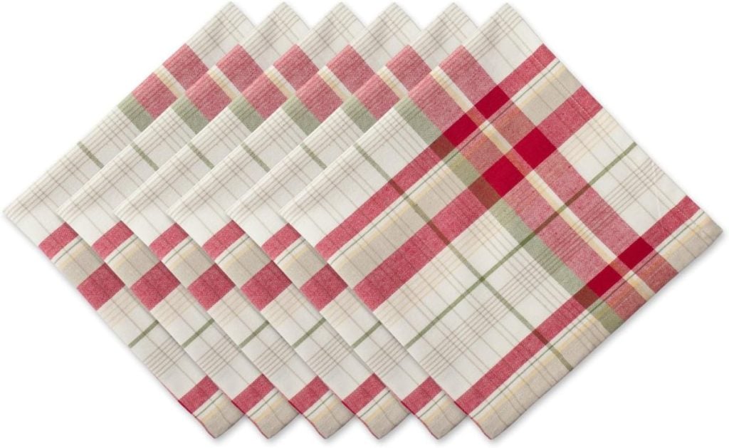 A set of ten cloth napkins arranged in a fan pattern, featuring a red, green, and beige plaid design on a white background.