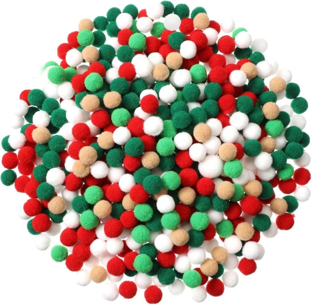 A pile of small, round craft pom-poms in red, green, white, and tan colors scattered in a heap.