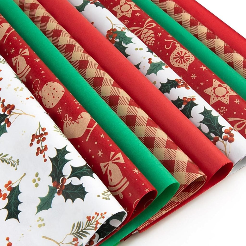 Rows of festive wrapping paper in red, green, white, and brown colors with holiday-themed patterns such as holly, pinecones, plaid, and ornaments—perfect for wrapping a thoughtful hostess gift.