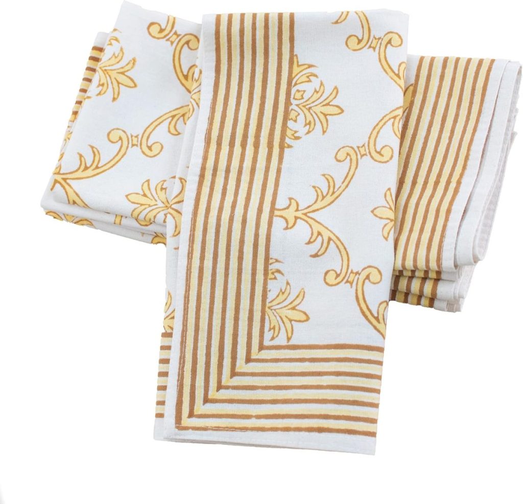 Folded white cloth napkins featuring gold decorative patterns and striped borders are arranged in an overlapping manner on a white background, reminiscent of elegant table settings with Mercury Glass Ornaments.