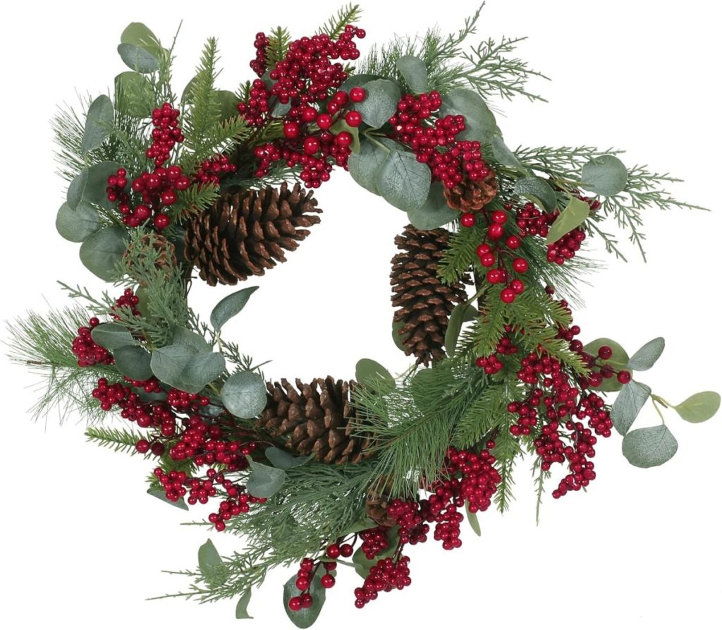 A holiday wreath decorated with pinecones, red berries, green leaves, and pine branches.