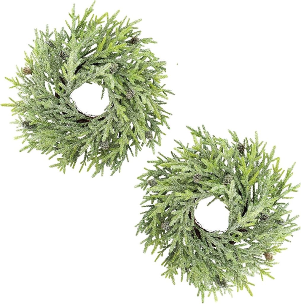 Two artificial green wreaths with frosted branches placed side by side on a white background.