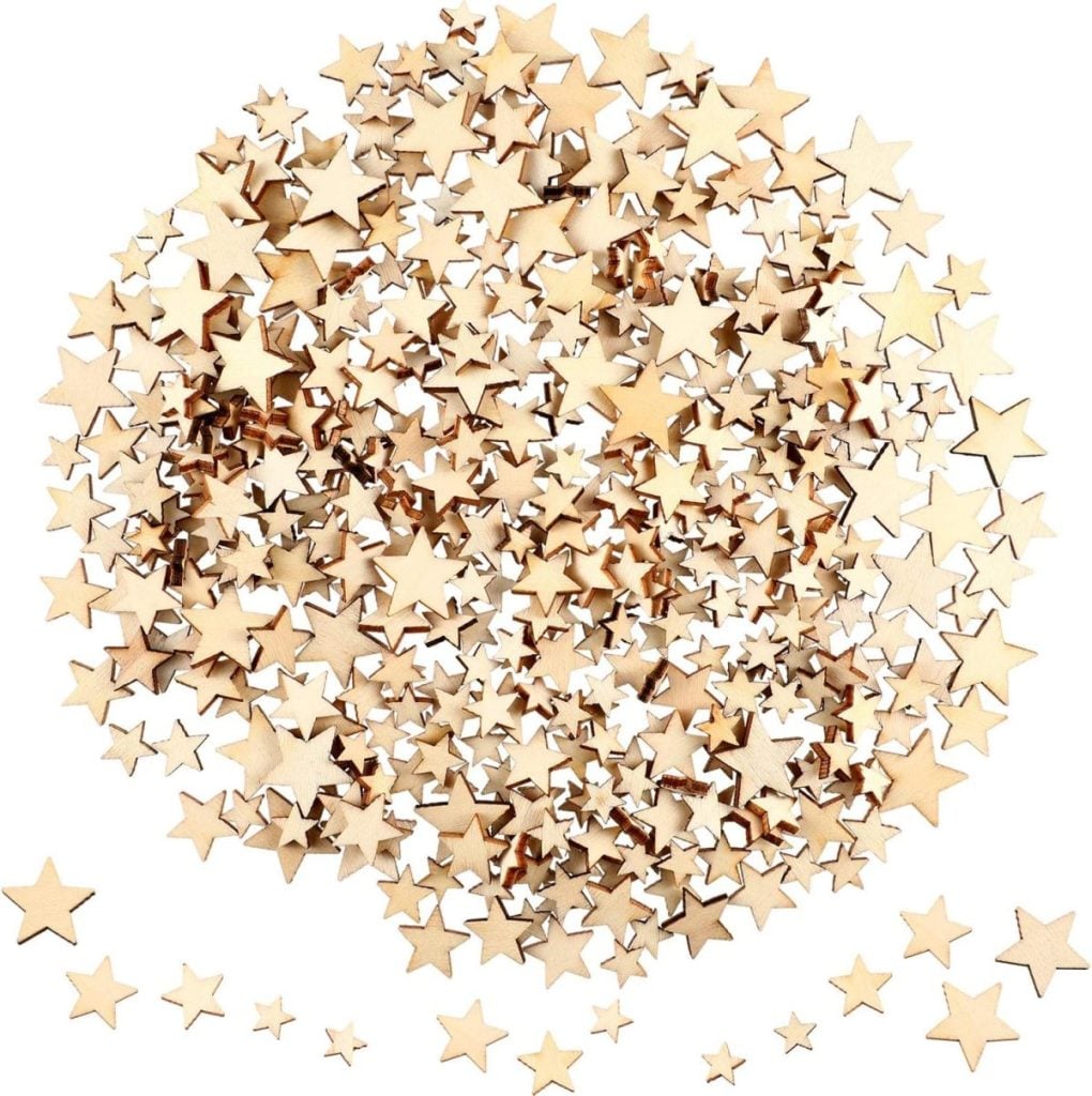 A large pile of small, light brown wooden star-shaped cutouts scattered on a white surface.
