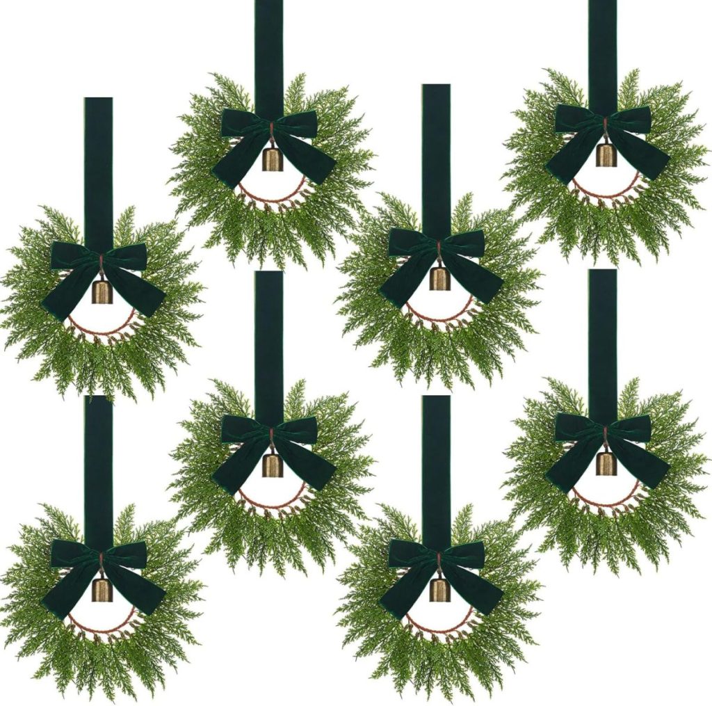 Eight identical green wreaths with black bows and small gold bells hang from dark ribbons against a white background.