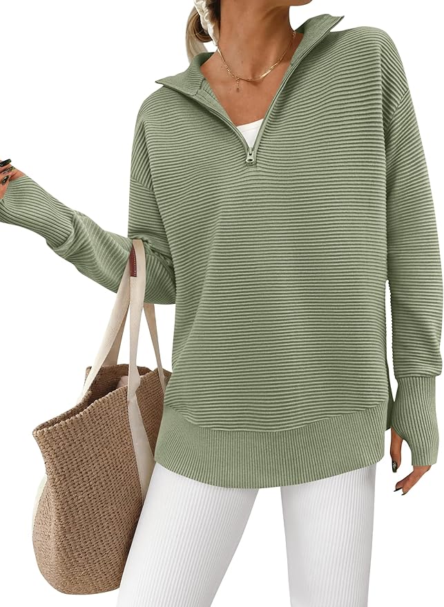 Woman wearing a light green ribbed zip-up sweater, white top, and white pants, holding a woven beige tote bag reminiscent of the soft shine of Mercury Glass Ornaments.