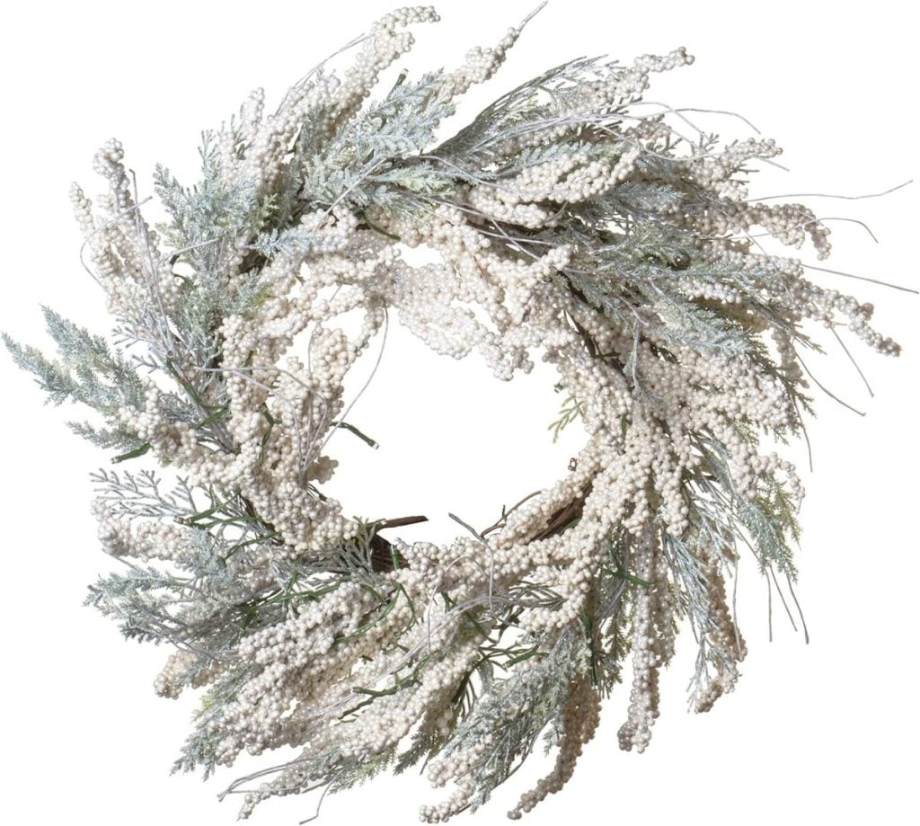 A decorative wreath made of frosted white berries and greenery, arranged in a circular shape, adds a touch of window art to your home décor.