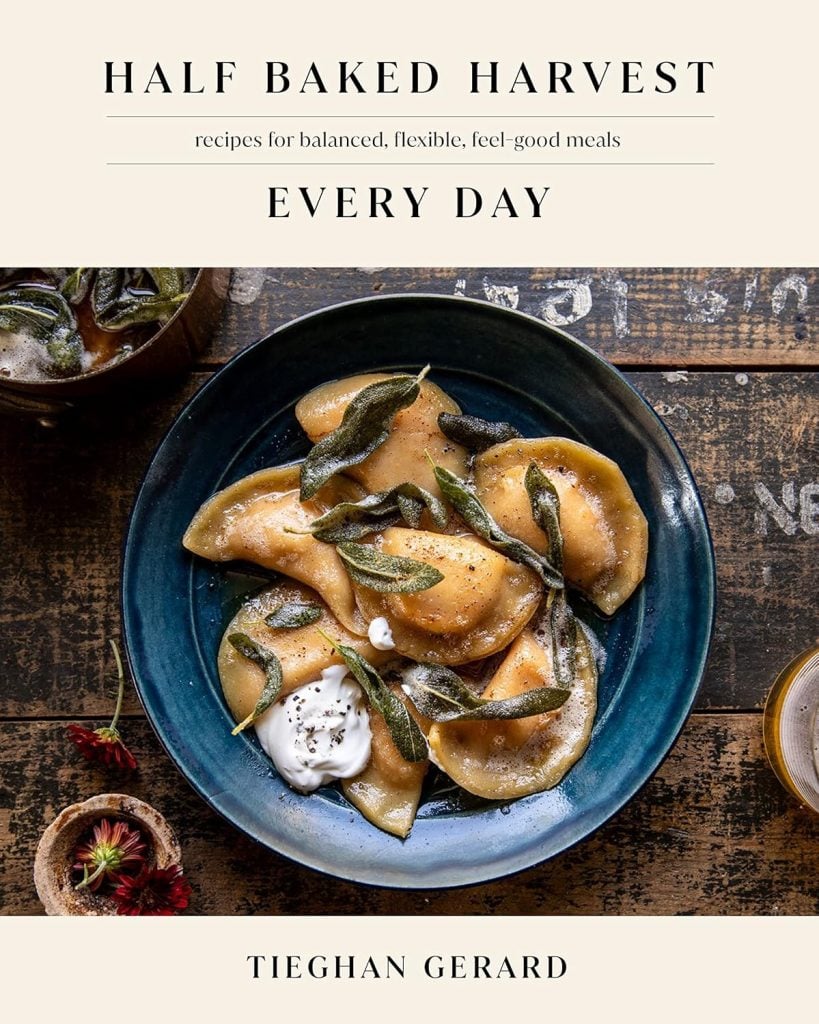 Cookbook cover titled "Half Baked Harvest Every Day" by Tieghan Gerard, featuring a bowl of dumplings with herbs and a dollop of cream on a rustic table.