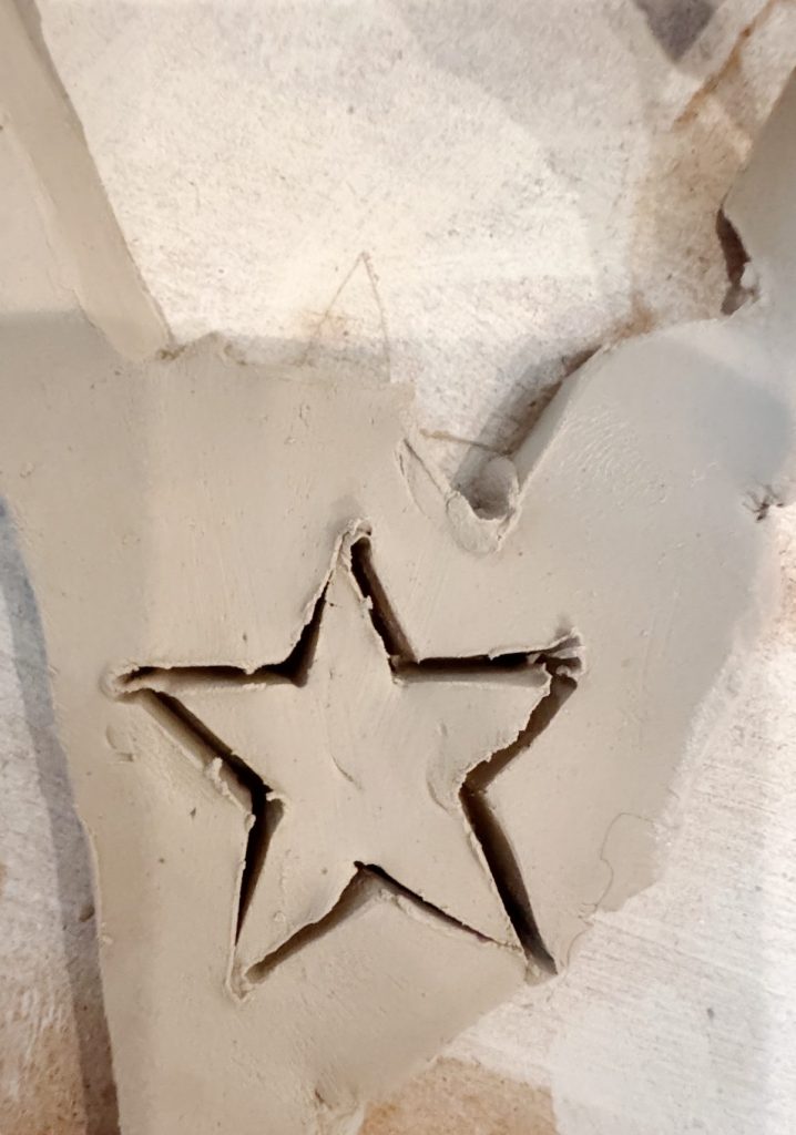 A piece of clay with a star shape cut out in the center, placed on a light-colored surface.