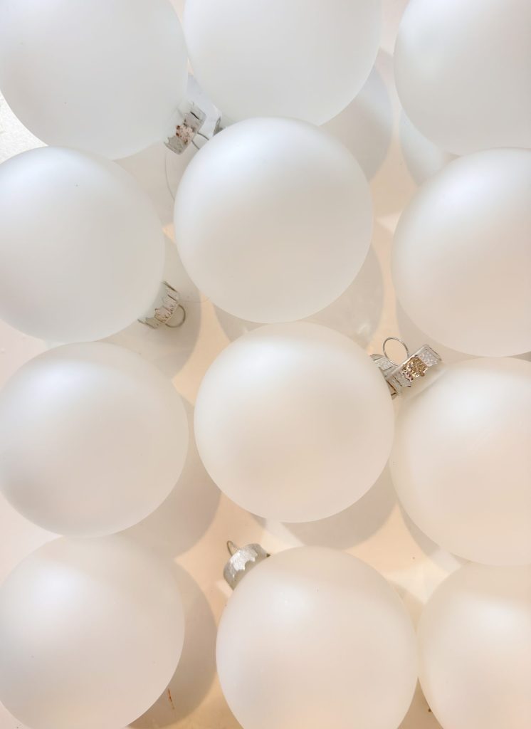 A group of matte white Christmas ornaments arranged closely together on a light surface.