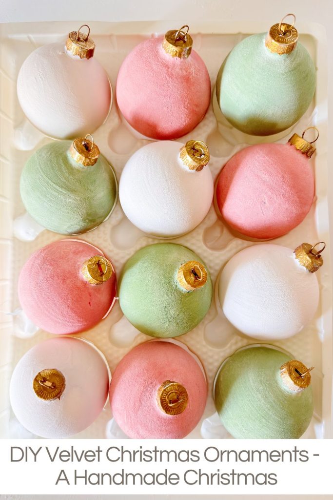 Twelve velvet-textured Christmas ornaments in pink, green, and white shades arranged in a tray. Text at the bottom reads: &ldquo;DIY Velvet Christmas Ornaments - A Handmade Christmas.&rdquo;.