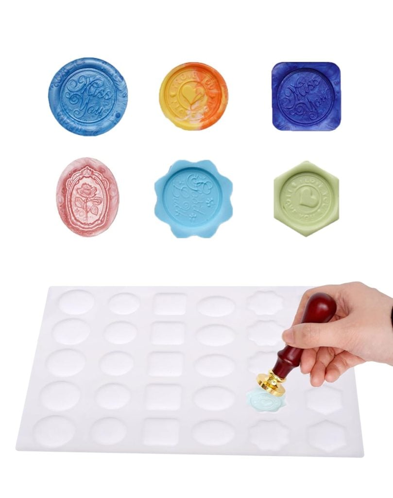 A hand uses a wax seal stamp on a silicone mold tray, with finished colorful wax seals displayed above the mold.