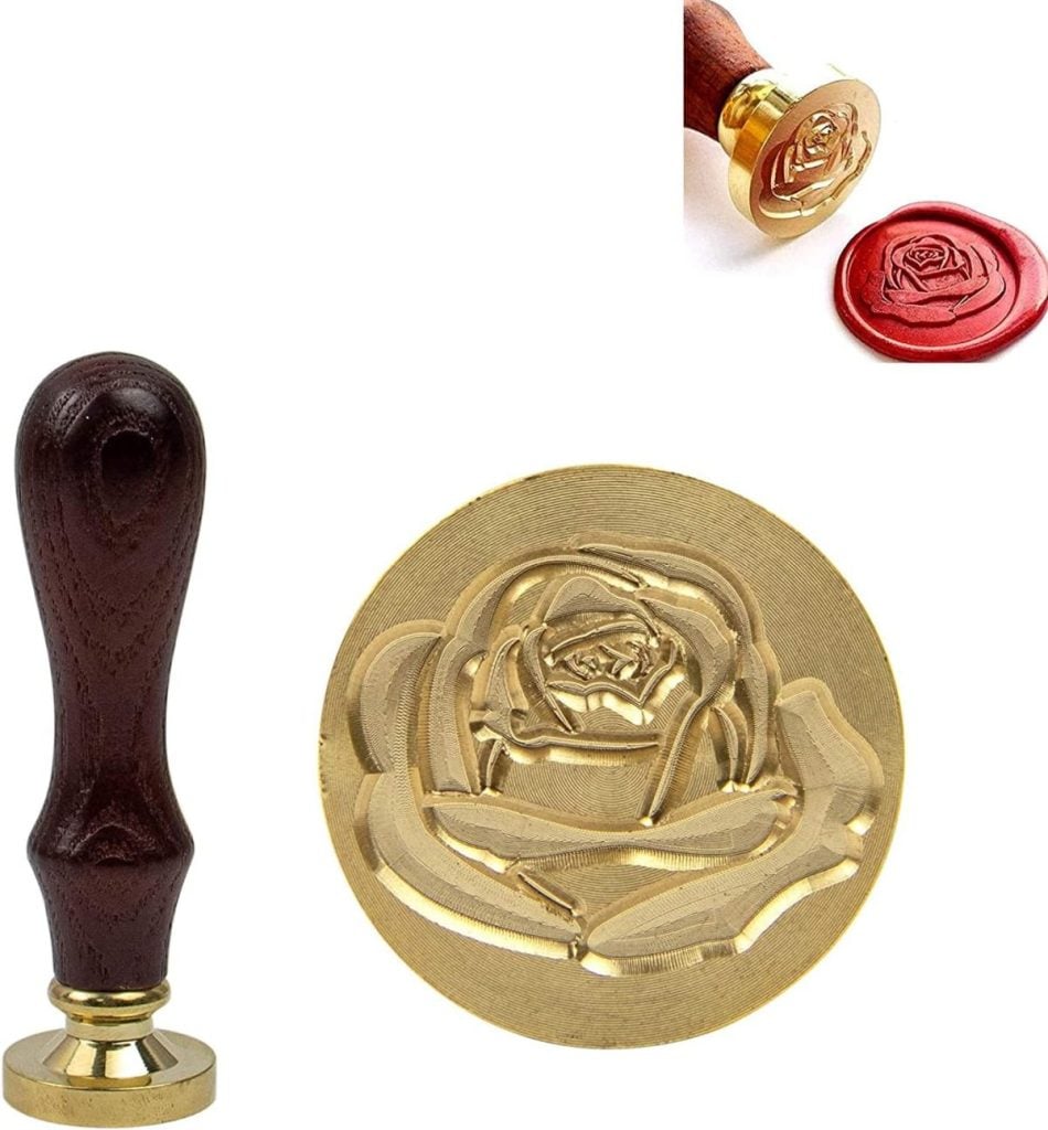 A brass wax seal stamp with a wooden handle, featuring a rose design, shown alongside a red wax seal impression of the same design.