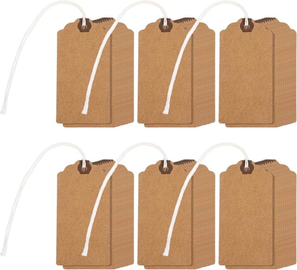 Six stacks of blank brown kraft paper tags with scalloped tops, each stack tied with a white string loop through a reinforced hole.