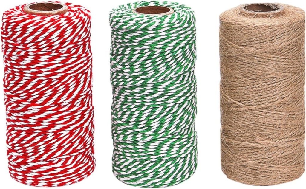 Three spools of twine: red and white, green and white, and plain brown, standing upright side by side against a white background.