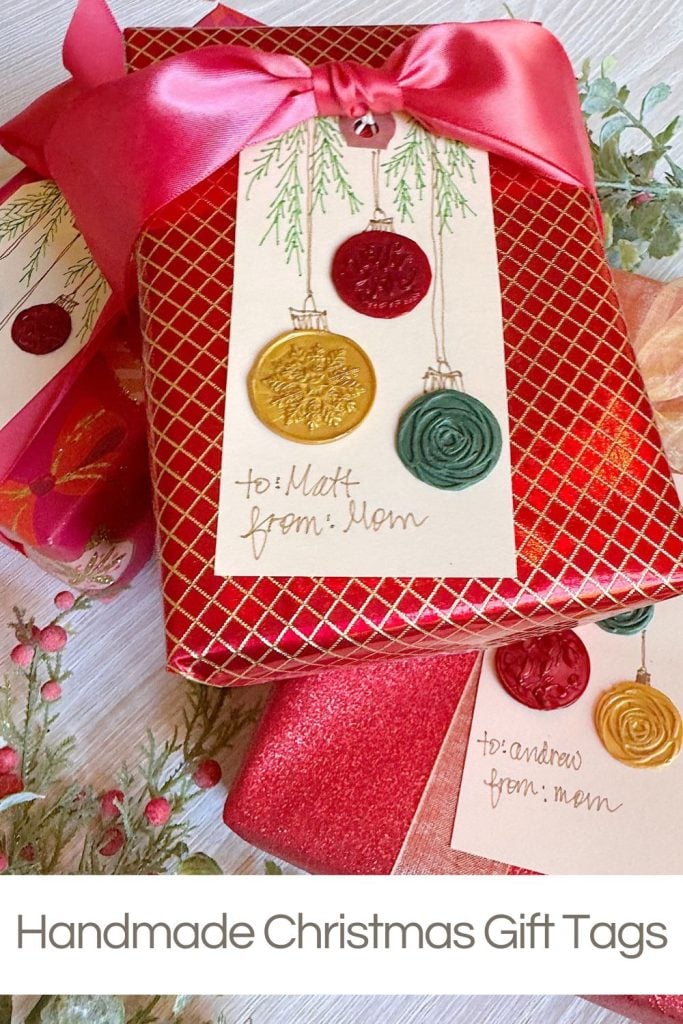 Two wrapped Christmas gifts with handmade tags featuring wax seals and handwritten "to" and "from" notes, decorated with a pink ribbon and festive greenery.