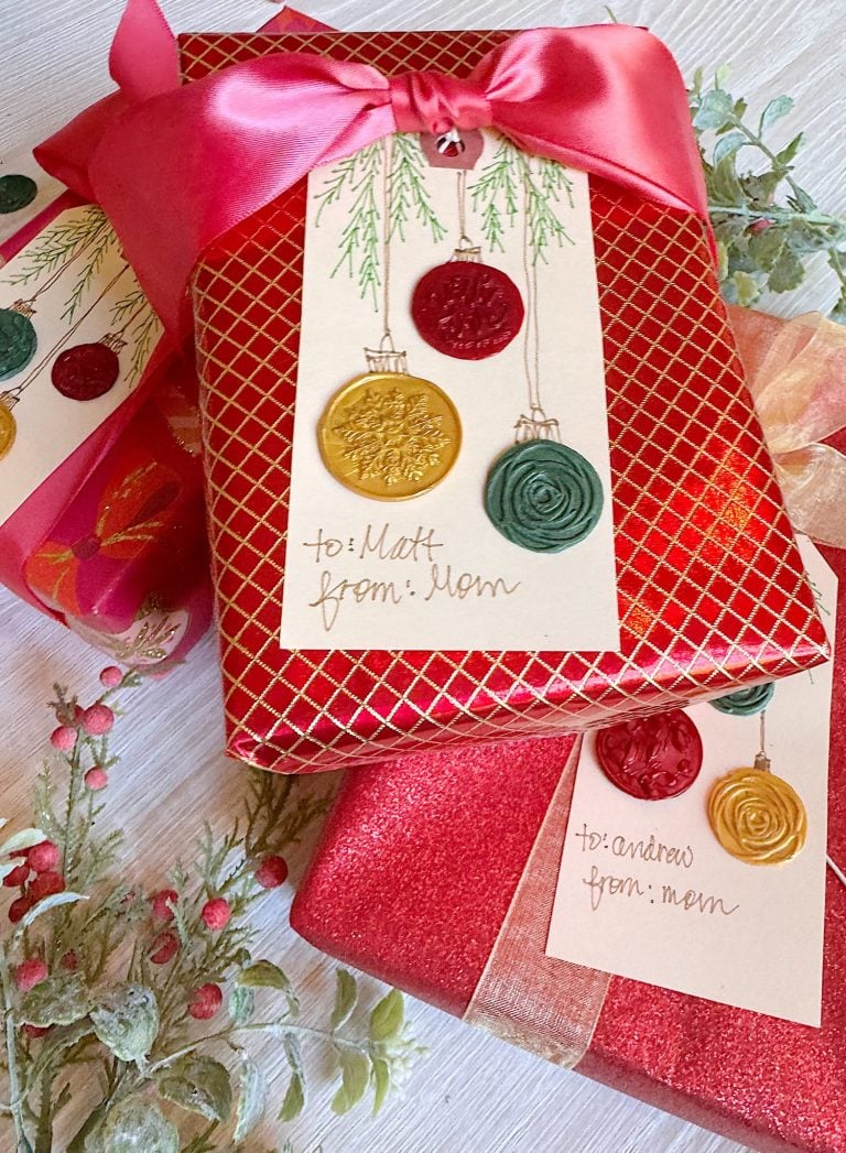 Two wrapped gifts with red and gold paper, decorated with large bows and handmade gift tags featuring wax seals and handwritten names from Mom to Matt and Andrew.