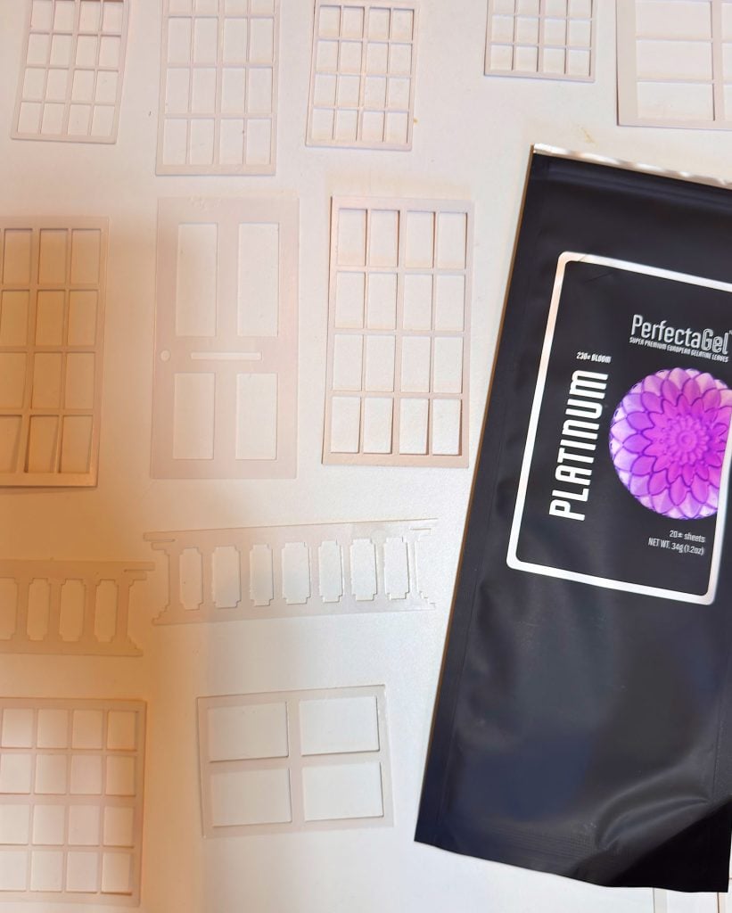 A black package labeled "PerfectaGel Platinum" is on a surface with several stencil outlines of doors and windows.