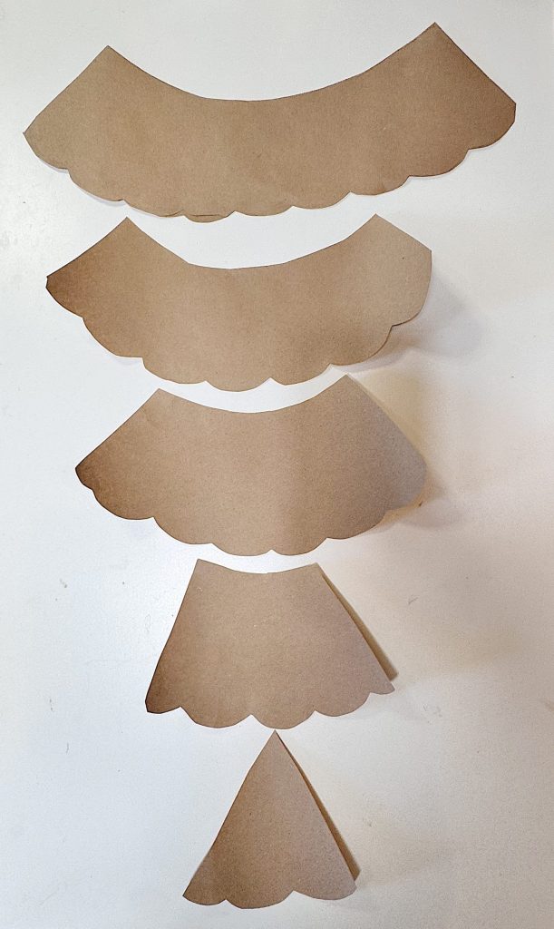Five brown paper semicircles with scalloped edges are arranged in descending size order from top to bottom on a white background.