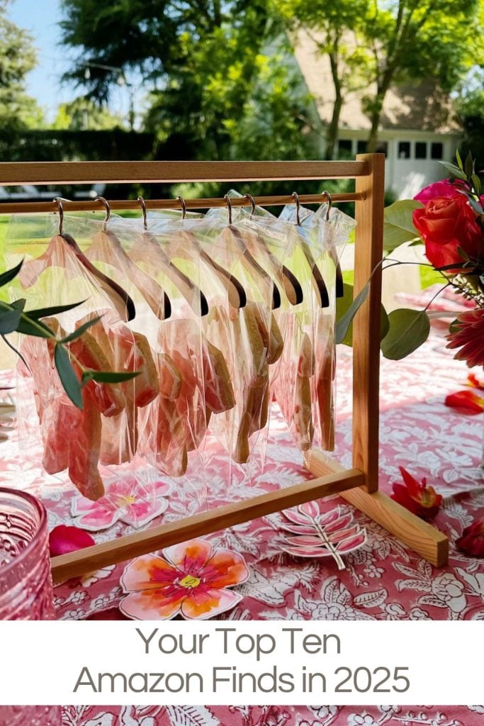 A wooden rack holds several clear plastic bags with what appear to be cookies shaped like leaves, displayed on a decorative pink tablecloth outdoors.