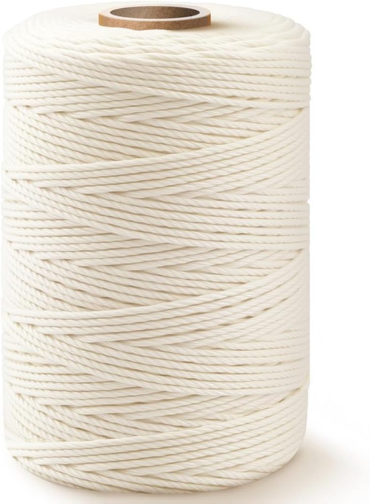 A large spool of white twine with a cardboard core, neatly wound in layers, standing upright against a plain background.