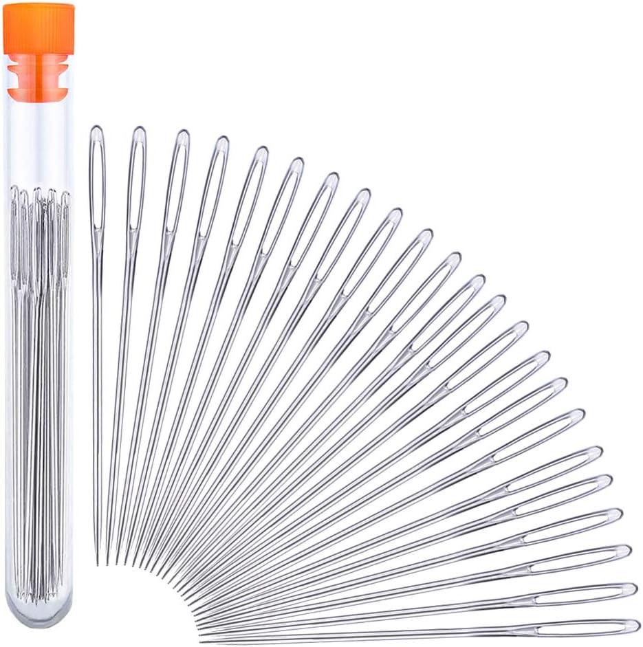 A set of metal sewing needles fanned out beside a clear plastic tube with an orange cap containing additional needles.