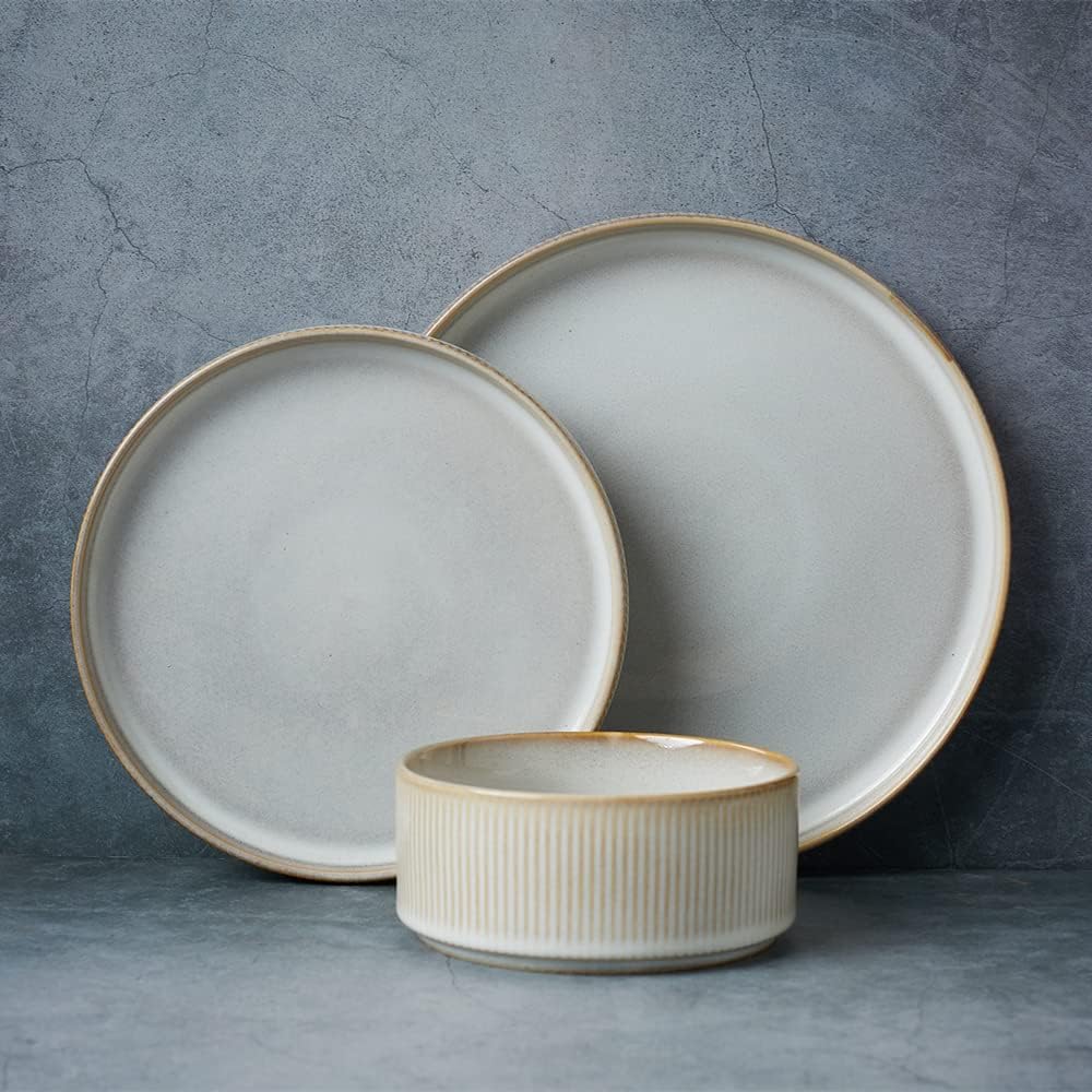 Two round, light gray ceramic plates and a matching ribbed ceramic bowl are arranged against a textured gray background&mdash;perfect inspiration for your list of stylish things to do this year.