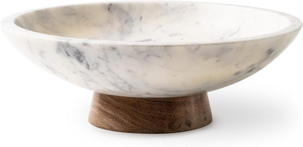 A shallow, round marble bowl with a white and gray pattern, set on a short, cylindrical wooden base.
