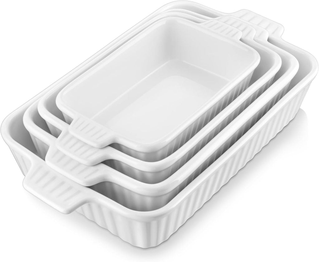 Four white ceramic rectangular baking dishes stacked inside each other on a white background.