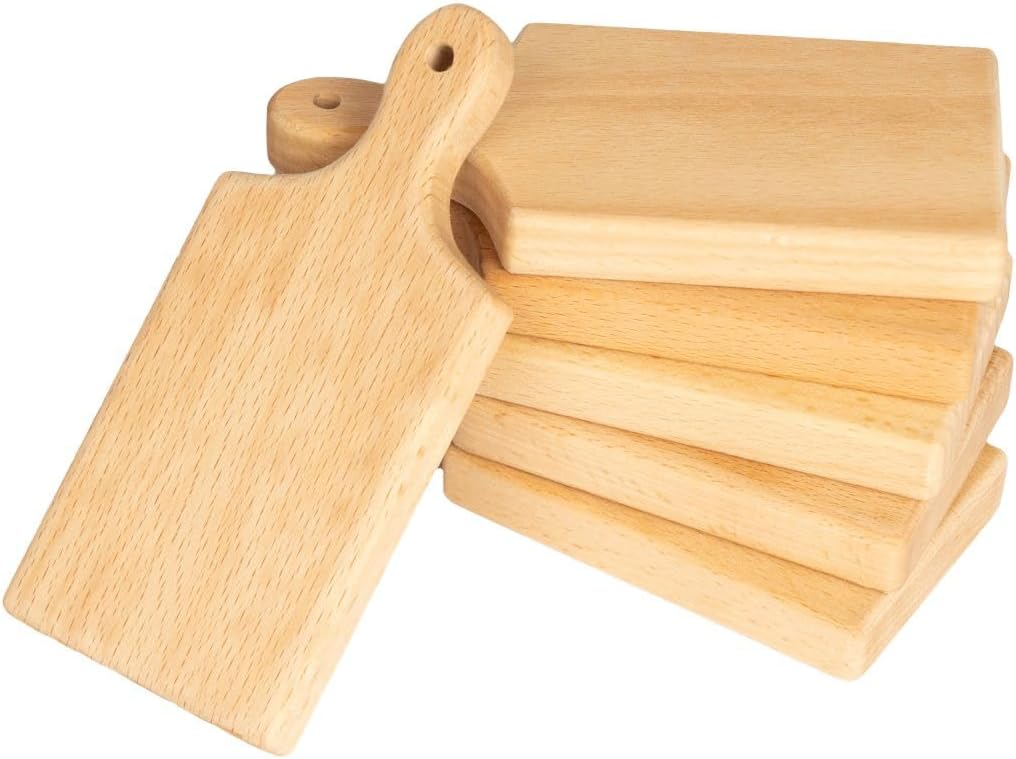 A stack of six light wooden cutting boards, one with a handle leaning on top of the pile.