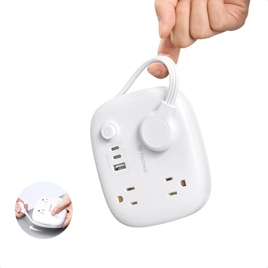 A hand holding a white square device.