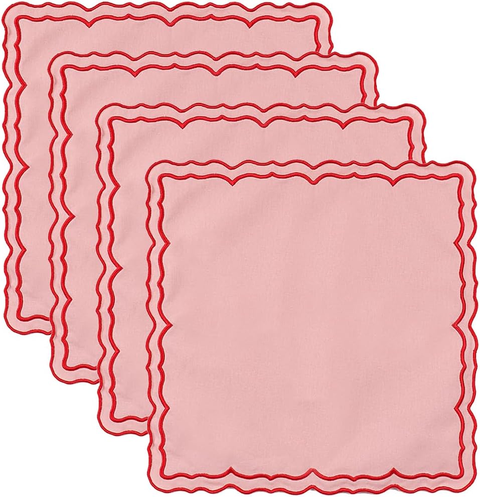 Four pink square cloth napkins with wavy red borders are stacked in a staggered arrangement against a white background.